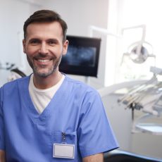 רופא שיניים מחייך במרפאת שיניים ונותן טיפים לשימור השיניים